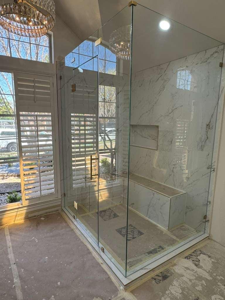 Primary bathroom remodel with a frameless glass shower, marble-look tile, green picket tile vanity wall and a chandelier