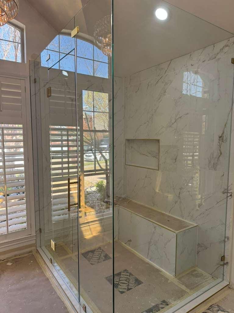 Primary bathroom remodel with a frameless glass shower, marble-look tile, green picket tile vanity wall and a chandelier