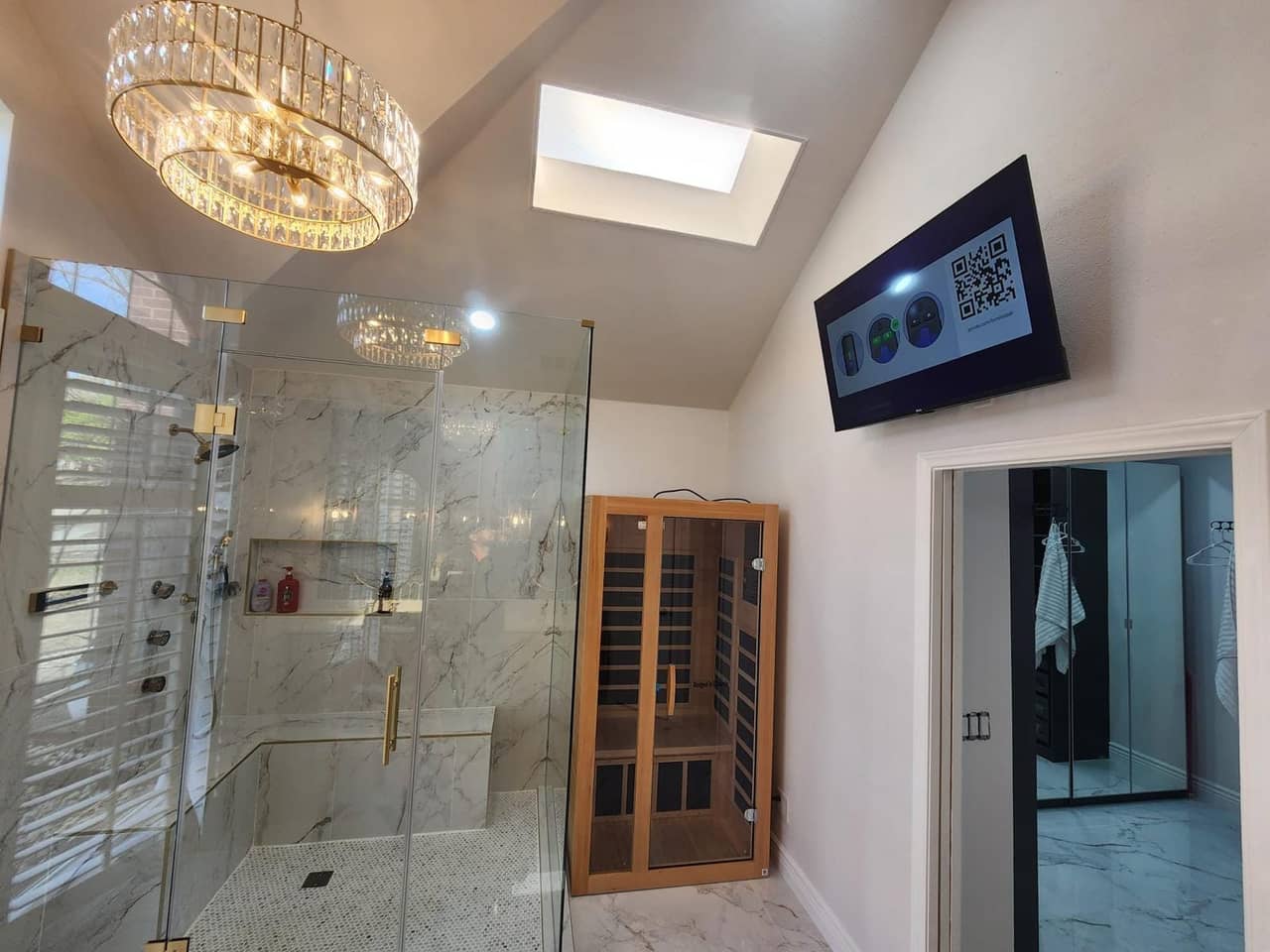 Primary bathroom remodel with a frameless glass shower, marble-look tile, green picket tile vanity wall and a chandelier