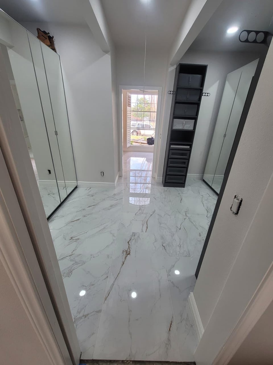 Primary bathroom remodel with a frameless glass shower, marble-look tile, green picket tile vanity wall and a chandelier