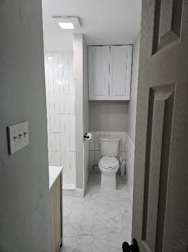 Bathroom remodel with large white wall tile, hexagon floor tile and a new toilet