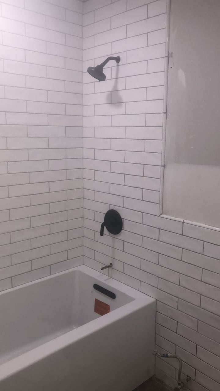 Bathroom tub and shower remodel with white subway tile and matte black fixtures